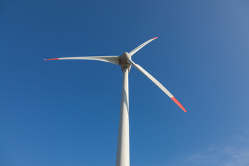 wind turbine with sun flare blue sky background view from below