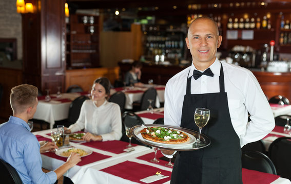 Waiter with tray in restaurant
