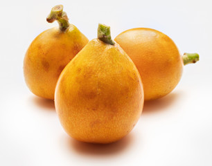Three fresh loquats (medlars). Isolated on white background. Close-up.