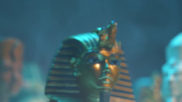 Dramatic shot of a pharaoh mask figure appearing in smoke.