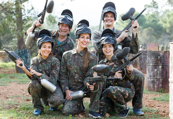 Portrait of cheerful team of paintball players with marker guns outdoors