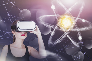 Young woman in VR glasses, atom hologram