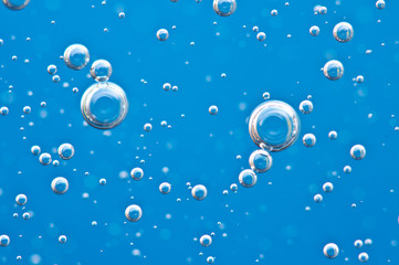 Bubbles of oxygen surging upward in blue water.