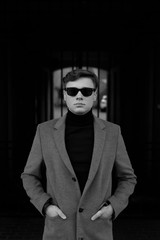 Black and white portrait of man with smart casual style. Sunglasses, polo neck and elegant jacket.
