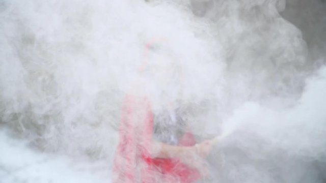 Thick smoke from smoky pomegranate in background standing fashion model in red suit in winter on snow captured n slow motion.