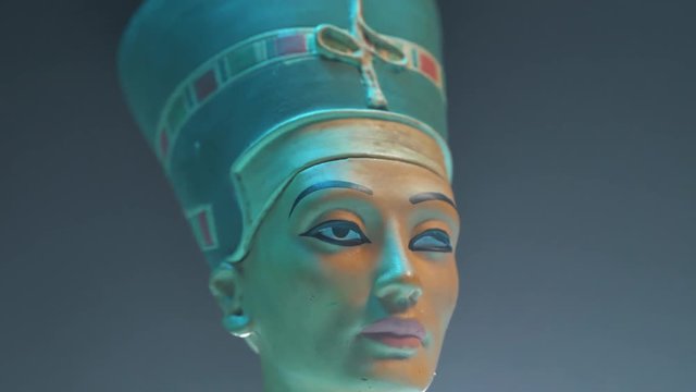 Dramatic shot of an Egyptian Nefertiti figure and smoke around.