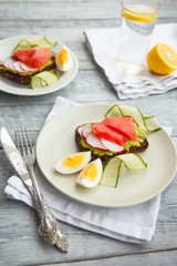 Toast sandwich with Salmon, Avocado,eggs and cucumber on wooden board.