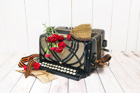 Accordion, red carnations, soldier’s cap, St. George ribbon and old letters. Victory Day. May 9