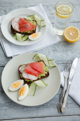 Toast sandwich with Salmon, Avocado,eggs and cucumber on plate on a table