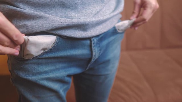 man shows turns empty pockets bankrupt no money. poverty Finance business bankruptcy concept. a man in old jeans looking for money in his pockets. crisis of getting into debt. problems and depression