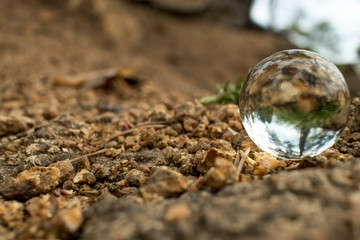 on beige granite pebbles there is a transparent ball in reflection of its nature and the surrounding world