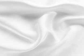 white silk texture. background of white fabric lying folds on the table