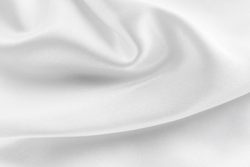 white silk texture. background of white fabric lying folds on the table