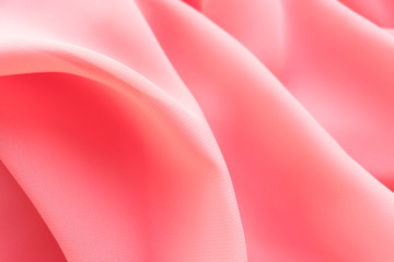 pink silk texture. background of coral fabric lying folds on the table