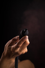 Hookah mouthpiece in a beautiful female hand on a dark background. Copy space.