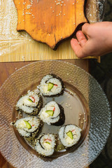 The woman cooked sushi and placed them on a round plate