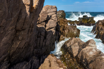 Obraz premium Phenomenal and scenic sea waves crashing against rocky coast. Sunny day during summer vacation. Beautiful force of nature.