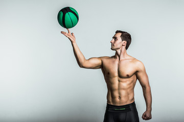 Muscle male model in black treand sportswear posing with a basket ball on gray background. Studio...