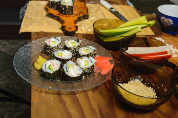 A plate with sushi roles in the kitchen, cooked by a woman's chef with her own hands