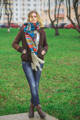 Portrait of a young woman in a city park in a scarf