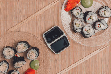 Sushi rolls on a round plate with sticks and soy sauce, top view