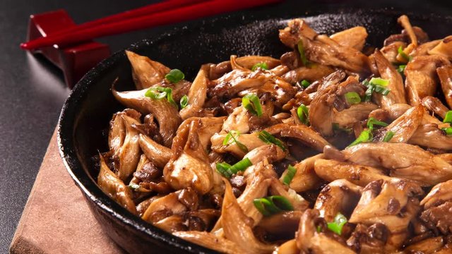 Close-up of delicious freshly cooked fried oyster mushrooms in a frying pan with smoke. Shitake.