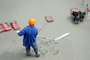 Des ouvriers en maçonnerie s'affairant sur une dalle de béton d'un immeuble en construction