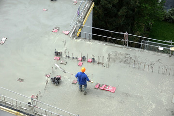 Des ouvriers en maçonnerie s'affairant sur une dalle de béton d'un immeuble en construction