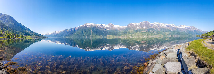An endless chain of mountains reflecting itself in a calm water of Eidfjord. Taller parts of the...