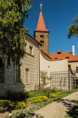 Fototapeta na wymiar Pruhonice, Czech Republic - April 22 2019: Vertical image of romanesque church of the Holy Virgin Birth with red roof is a part of Pruhonice park area. Sunny spring day with blue sky and flower beds.