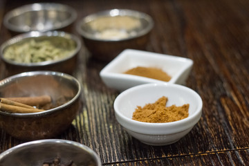Closeup of a variety of spices in metal bowls for making Masa tea in a yoga studio
