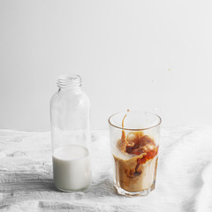 Bottle with milk and glass cup with coffee on the table. cold brew iced coffee