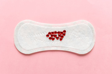 Menstrual pad with red heart glitter on pastel colored background. Minimalist still life