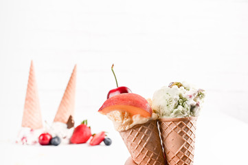 Sweet ice cream in balls on a white background. Dessert with different flavors and fresh berries. Ice cream in a waffle cone. Copy space.