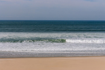 Calm panoramic seaside with beach. Peaceful ocean landscape. Tropical shore with empty beach. Surf on sandy beach. Summer vacation concept.