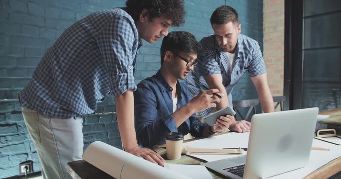 Student working on project. Group of diverse people in early 20s collaborating on an architecture plan, discussing plans and ideas, brainstorming in modern office - slowmotion 4k