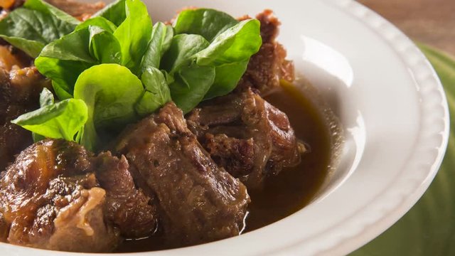 Slide shot Brazilian traditional food called oxtail with arugula. Smoke.