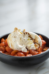 Burrata Büffelmozzarella Kugel mit Tomaten, Olivenöl und Balsamico auf schwarzen Teller