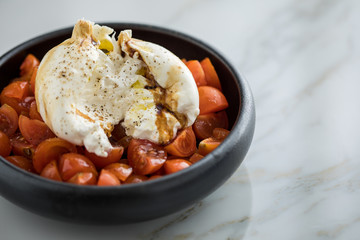 Burrata Büffelmozzarella Kugel mit Tomaten, Olivenöl und Balsamico auf schwarzen Teller