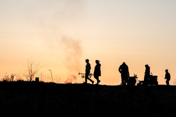 Fototapeta premium The main theme of this photo is the shadow and silhouettes of people against the backdrop of the sunset. Sunset on the bay. People relax, walk. Family roasts meat.