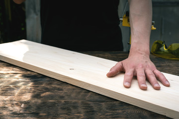 Worker is holding a wooden bar on a workbench. Woodwork. Carpentry.