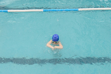 top view of a 7-year boy playing and swimming in the swimming pool