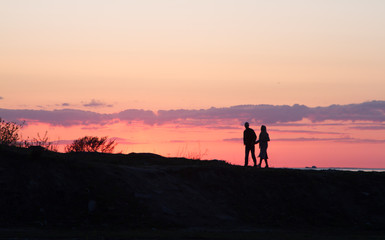 Fototapeta premium silhouette of man and woman walking on beach at sunset