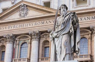The statue of Saint Paul near the entrance of Saint Peter's cathedral, Basilica di San Pietro in Vatican, Rome, Italy. Facade of Saint Peter's cathedral on the background, bihind the sculpture statue.