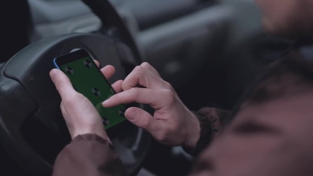 close up - hands of man using smartphone  with green screen  in the car.