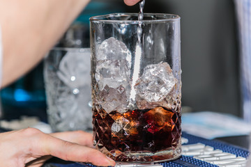 Closeup of barman hand putting on a glass to prepare cocktail.