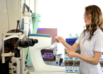 pretty young woman undergone an ocular fundus inspection with ophthalmologist optometrist optician, low depth of field