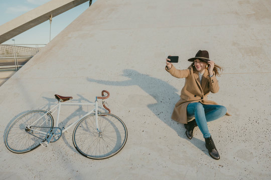 Young hipster woman near to a bicycle making a selfie