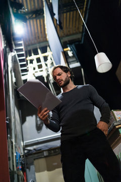 Actor with script rehearsing backstage