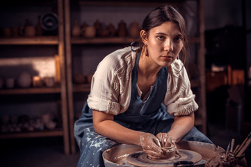 Charming pottery master shows how to work with clay and pottery wheel. Handicraft production.